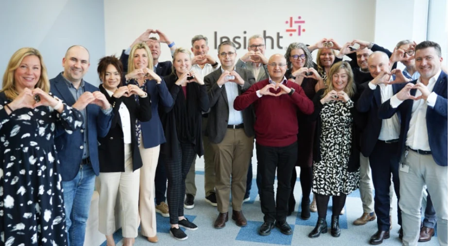 Insight team members smiling and making heart-hand gestures in front of a branded wall