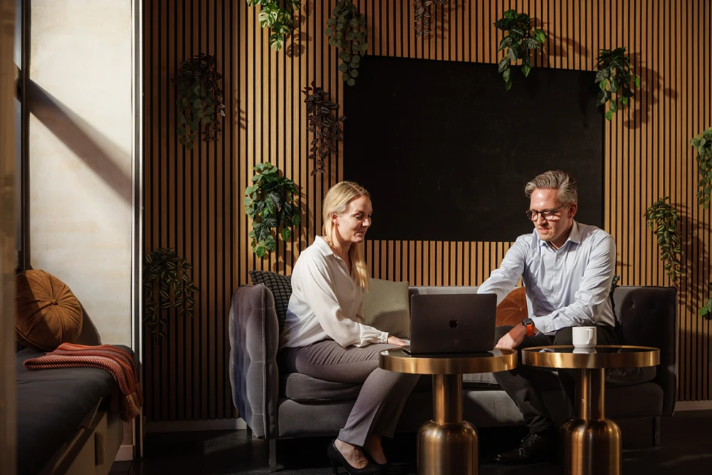 A professional man and professional woman having a meeting looking at a laptop